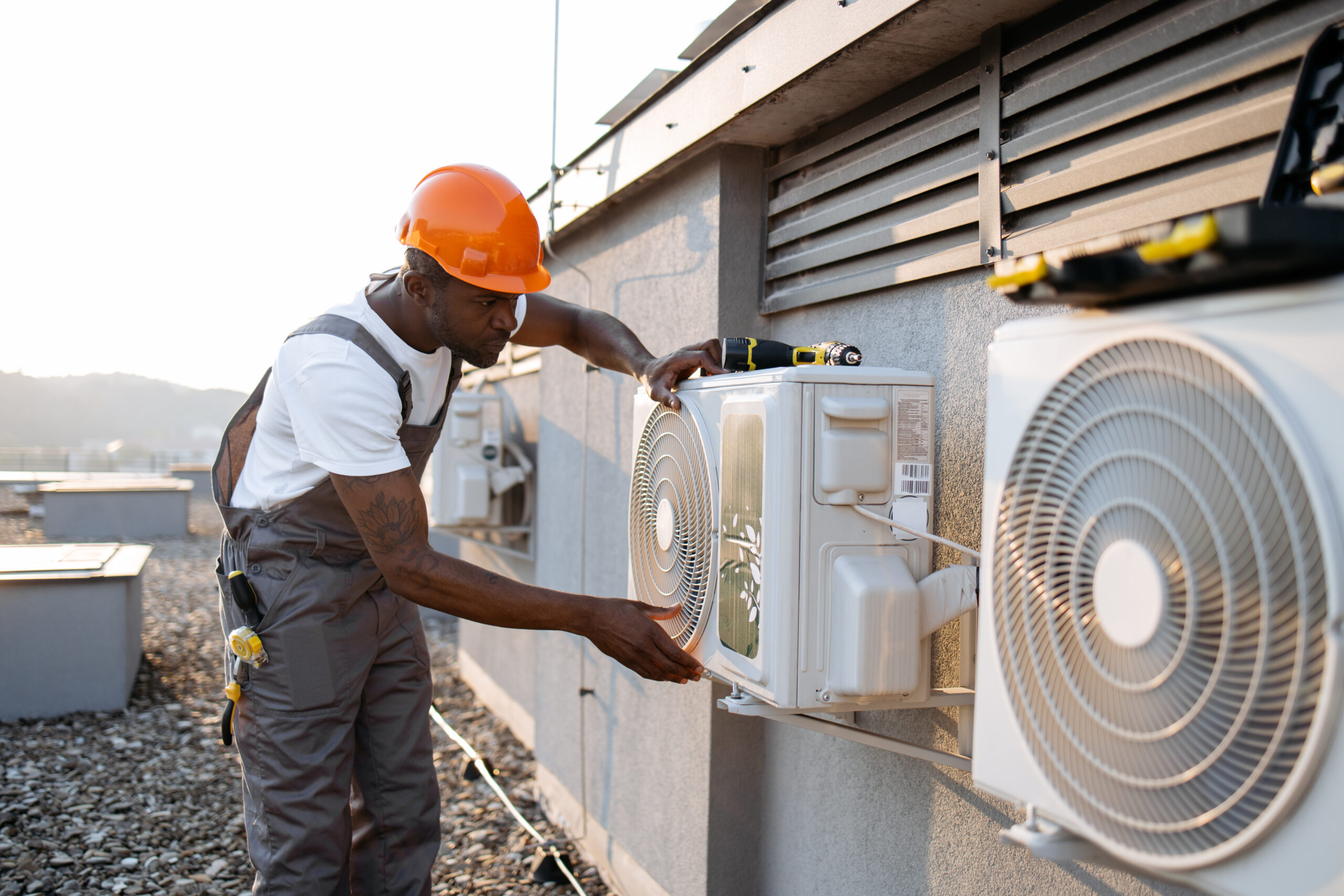 African man in uniform checking air conditioner on plant